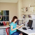 Femme en télétravail devant son cahier et son ordinateur à côté d'une Imprimante multifonction Xerox C315.